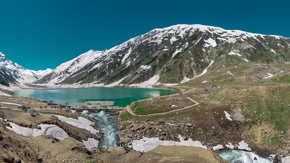 A glacier-fed lake surrounded by snow-capped mountains.