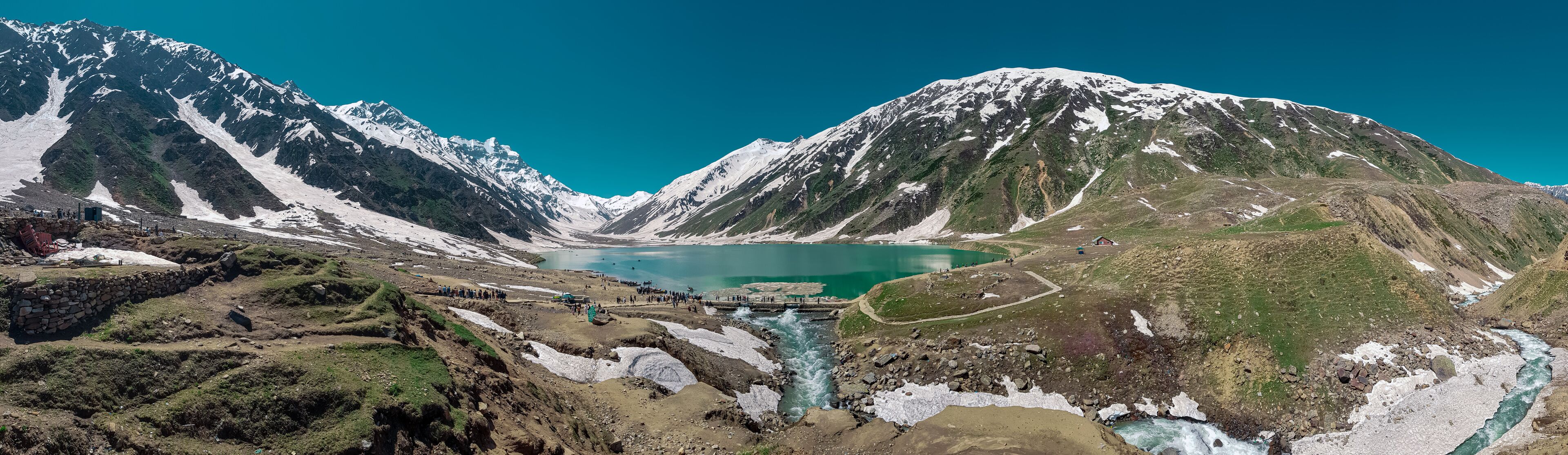 A glacier-fed lake surrounded by snow-capped mountains.
