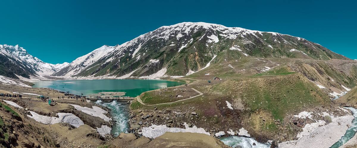 A glacier-fed lake surrounded by snow-capped mountains.
