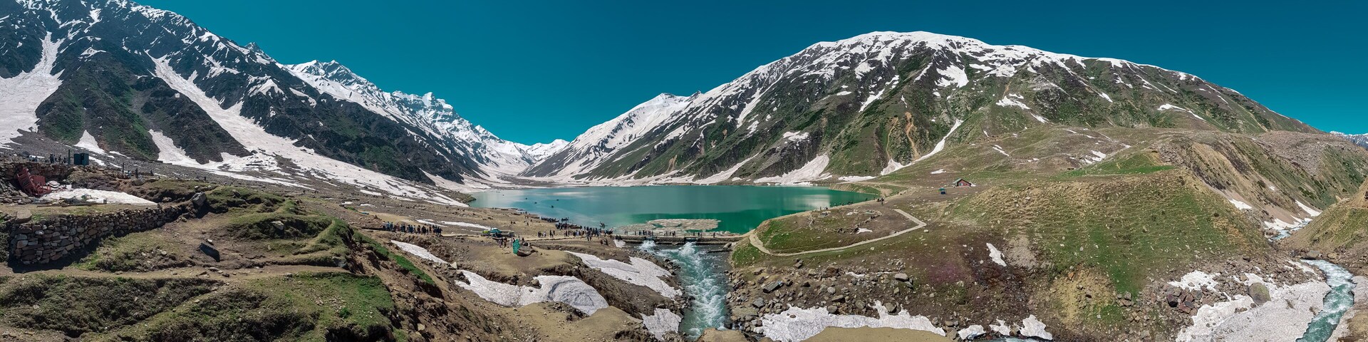 A glacier-fed lake surrounded by snow-capped mountains.