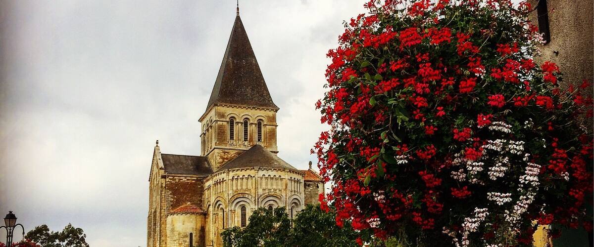 A historic church with a pointed steeple, surrounded by vibrant flower boxes.