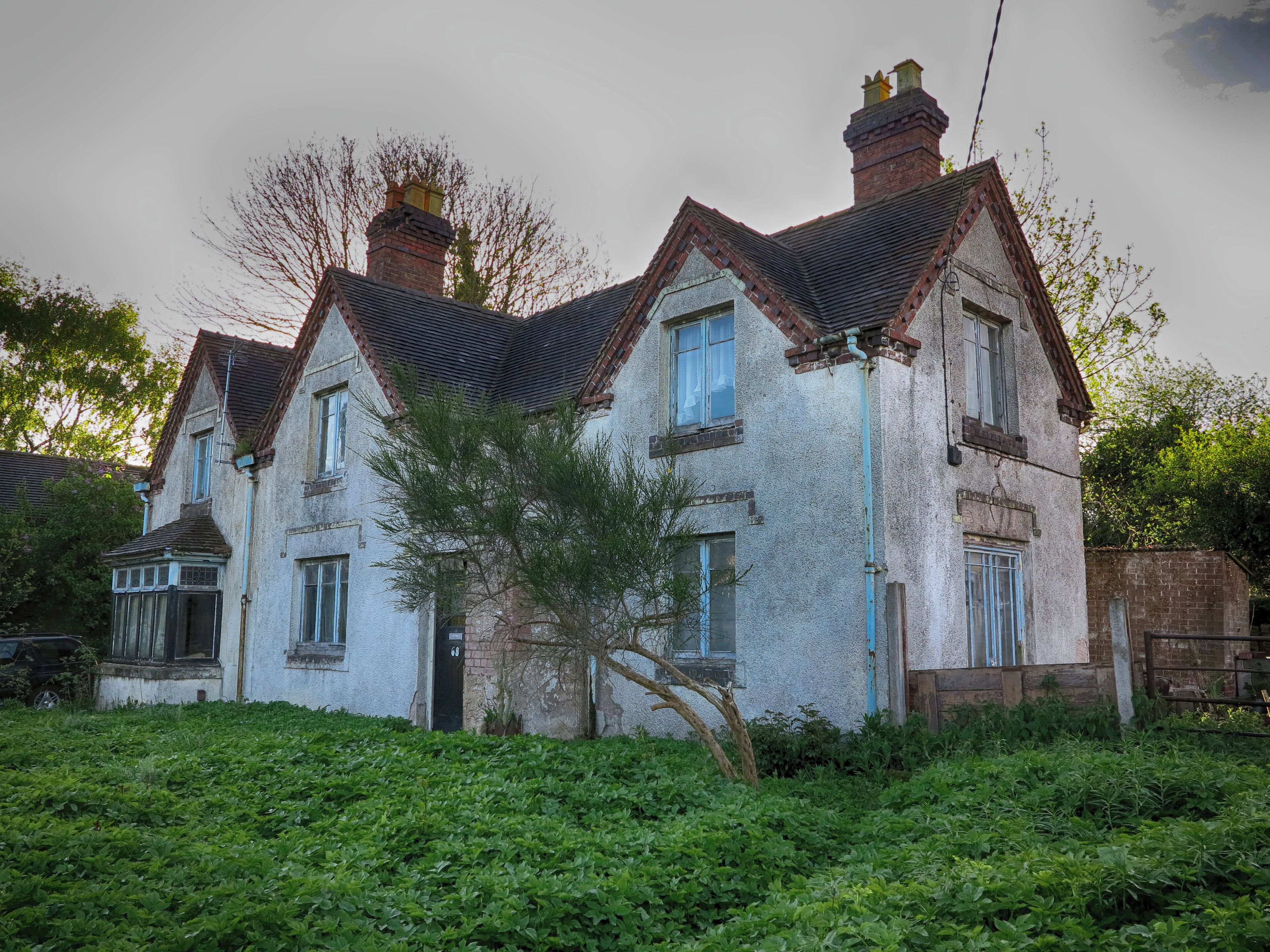 A large, two-story house with a steeply pitched roof and multiple chimneys.