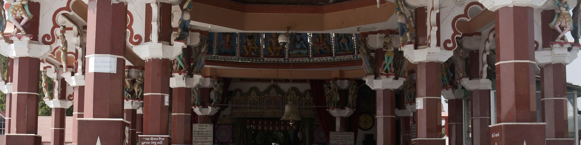 Entrada de um templo com pilares ornamentados, estátuas e esculturas detalhadas.