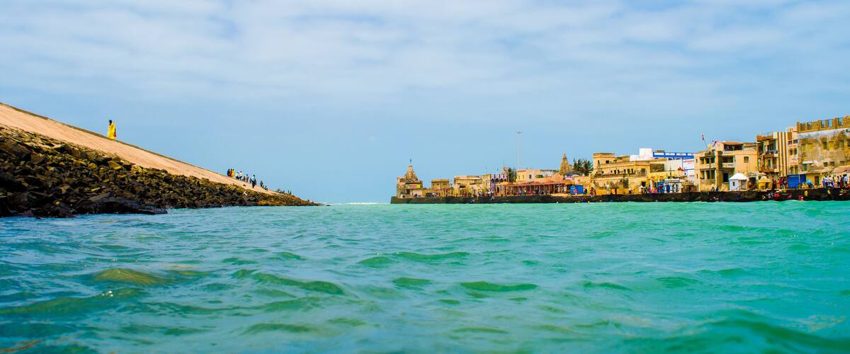 A coastal town with a rocky shoreline, clear turquoise waters, and a mix of traditional and modern buildings.