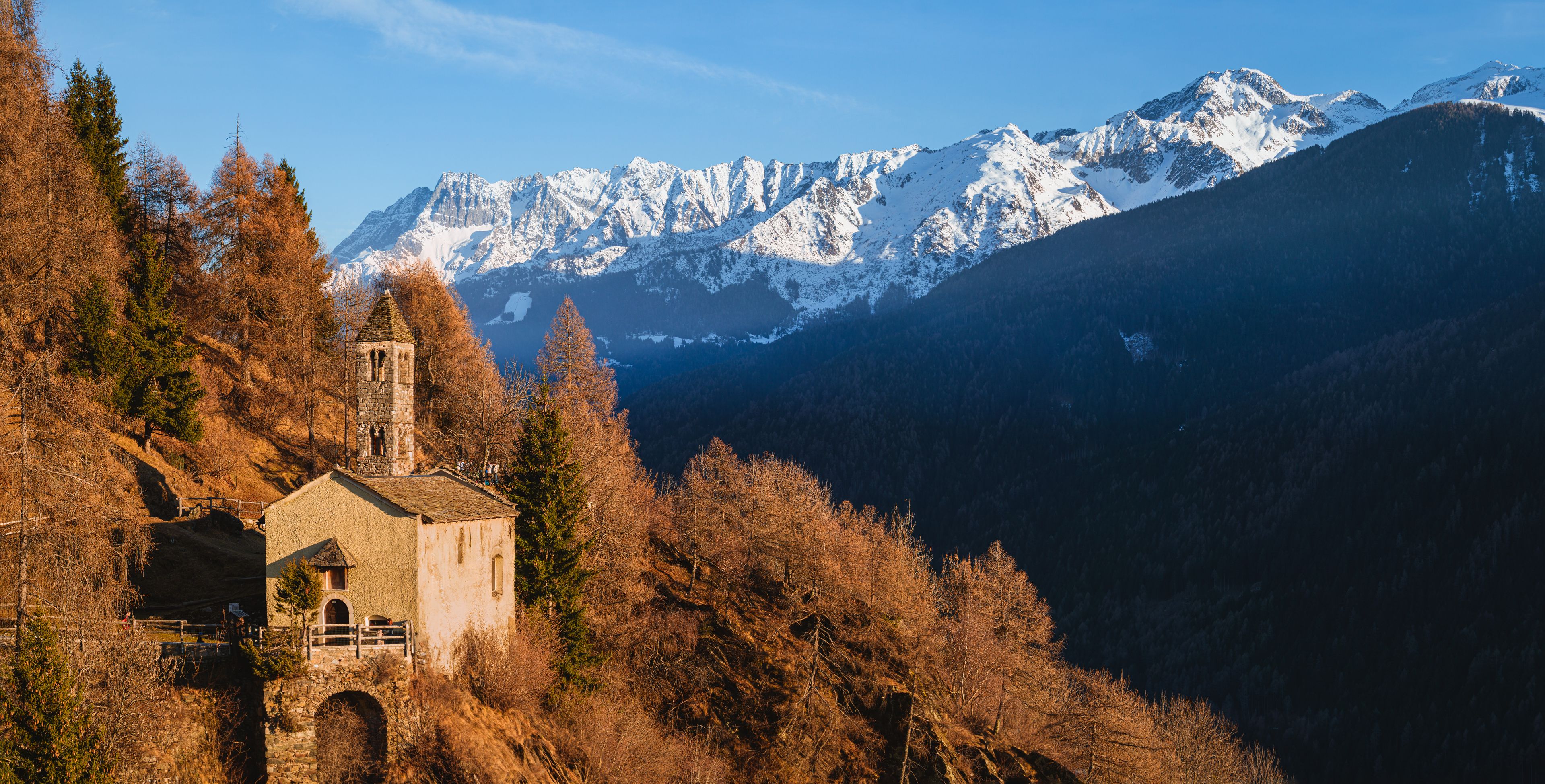 The church of San Clemente, in the mountains of Val Camonica with the setting sun, near the town of Vezza d'Oglio, Italy - January 2022.
