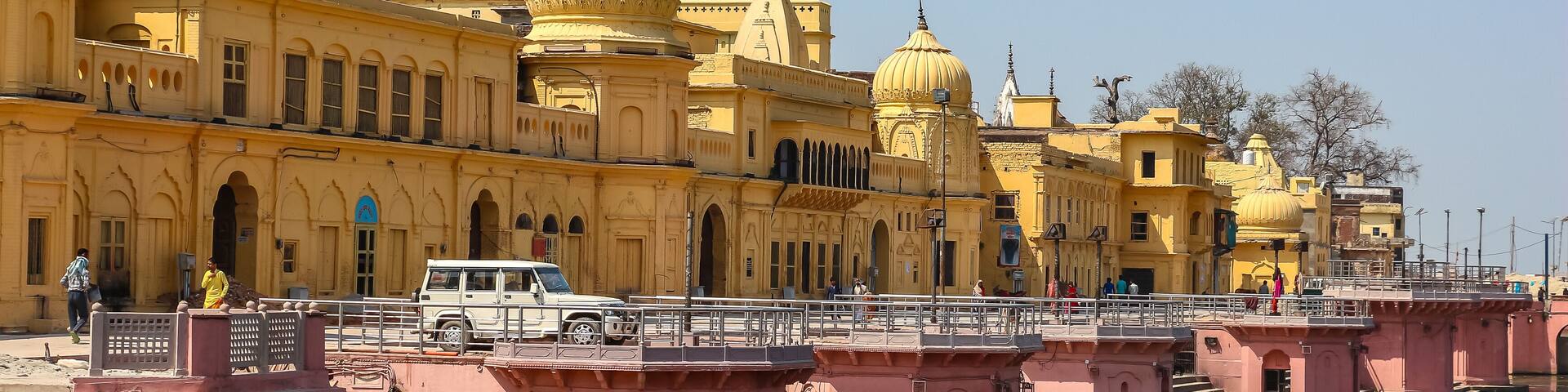 A yellow building with domes and a bridge over a river.