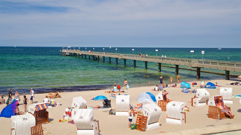 A beach with lounge chairs, umbrellas, and a pier extending into the ocean.