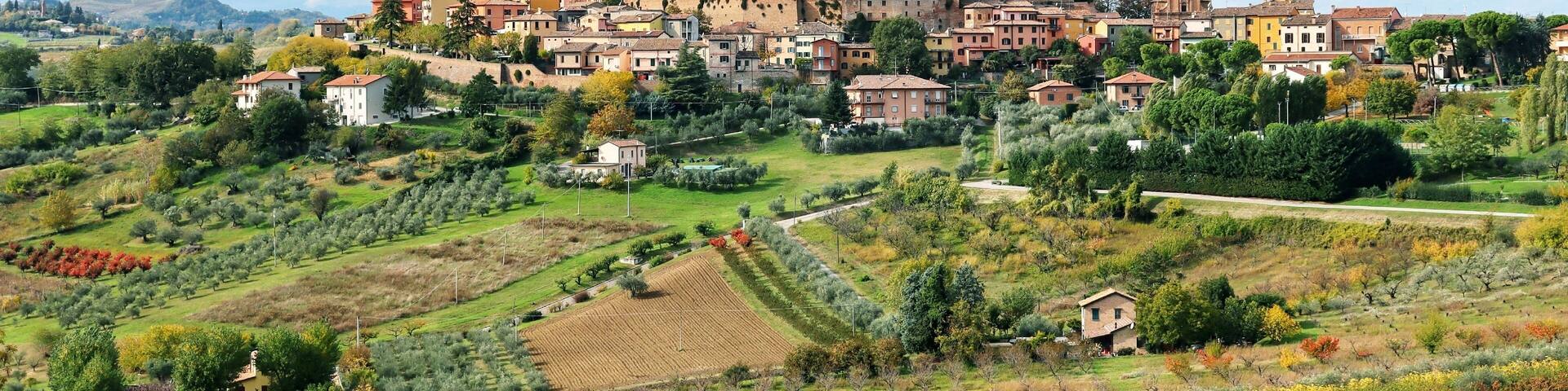 Beautiful landscape with small old town on the hill and surrounded by colorful autumn agriculture field against cloudy sky during autumn in Longiano,Province of Forli-Cesena,Italy