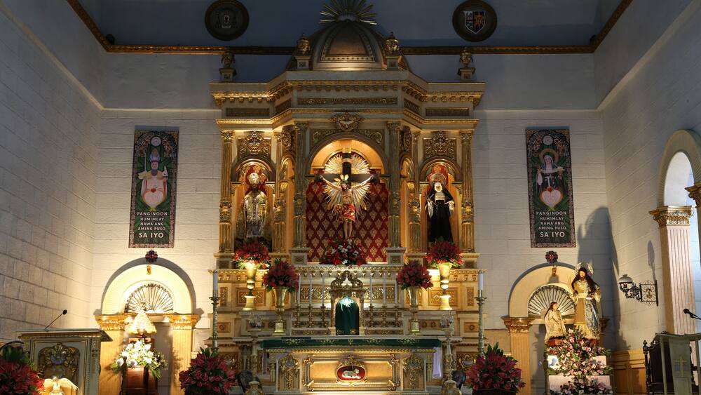 An ornate religious altar with statues and floral arrangements.