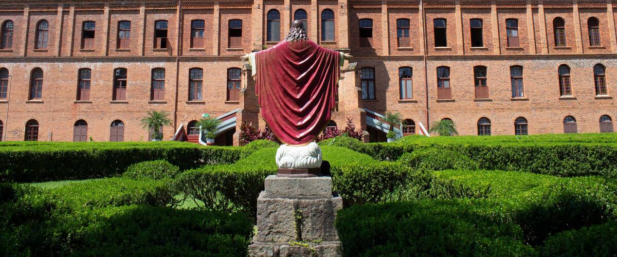 A large brick building with arched windows and a statue in front.