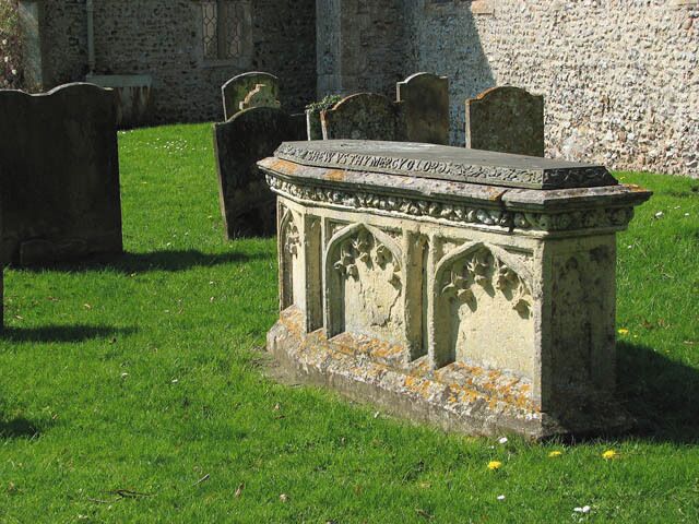 St Mary's - ornate tomb in churchyard. St Mary's church > 1263631 - 1263635 - 1263650 is tucked away on the edge of the village, located off the narrow Station Road and linked with it by an unsurface lane which is even narrower. The church can't be seen from a distance because there is no church tower giving away its location. Restored in Victorian times, there still is the original 13th century doorway, and the square font > 1263655 dates from Norman times. The royal arms to George III > 1263638 are described as being some of the finest in the county; a couple of medieval bench ends > 1263648 are adorned with carved figures and animals and the nave roof is of arch-braced hammerbeam construction. The church is open every day - if you can find it.