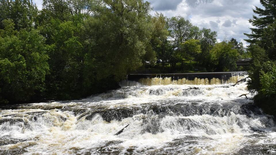 A turbulent river with a bridge in the background.