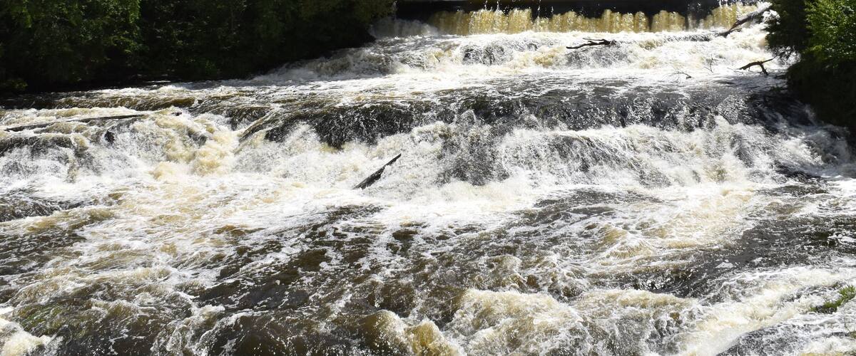 A turbulent river with a bridge in the background.