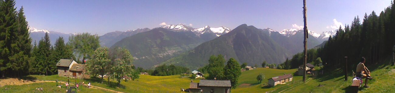 A mountainous landscape with houses, trees, and a clear sky.