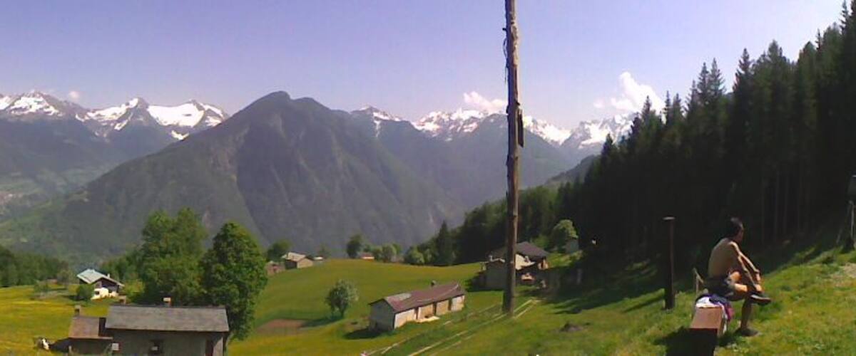 A mountainous landscape with houses, trees, and a clear sky.