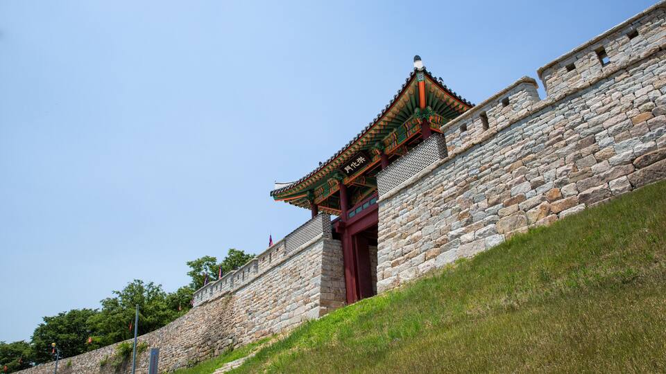 A traditional stone wall with a tiled roof and a red door.