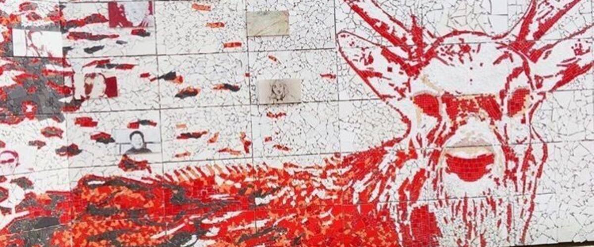 A wall with a red deer mural and scattered red and black tiles.