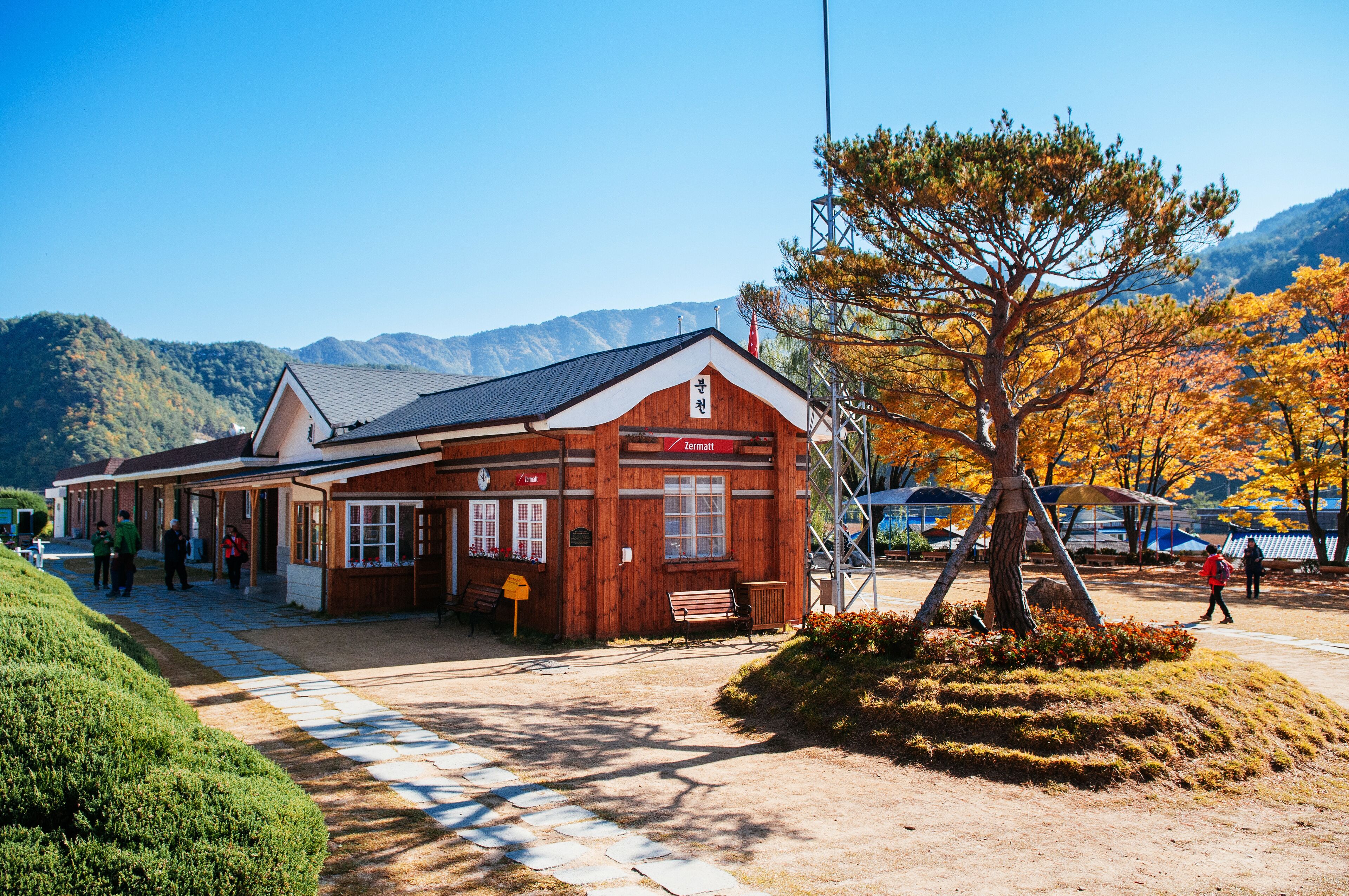 A wooden building with a sign reading "Zermatt" in a mountainous area with autumn foliage.