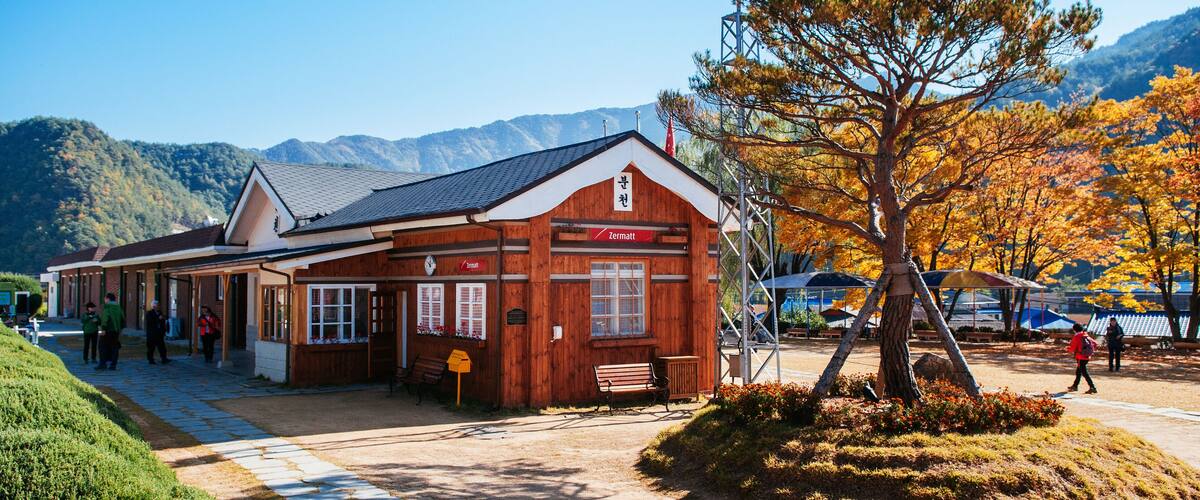 A wooden building with a sign reading "Zermatt" in a mountainous area with autumn foliage.