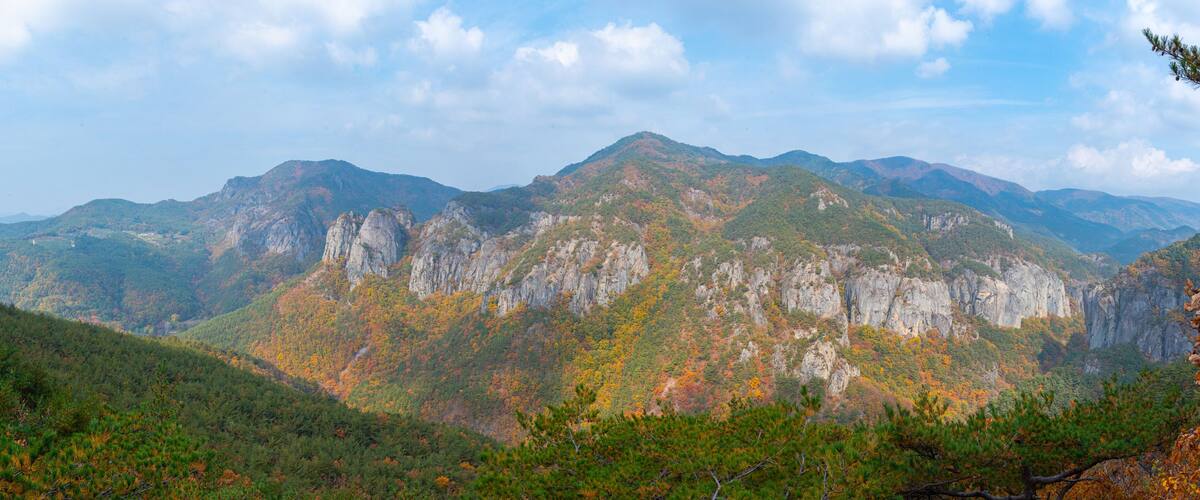 A mountainous landscape with autumn foliage and rocky cliffs.