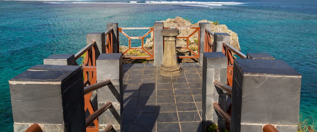 A stone staircase leading to a coastal overlook with a view of the ocean and a clear sky.
