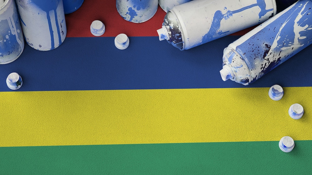 Mauritius flag and few used aerosol spray cans for graffiti painting. Street art culture concept, vandalism problems