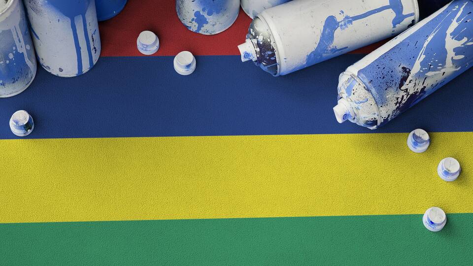Spray paint cans and caps on a surface with horizontal stripes of blue, yellow, and green.