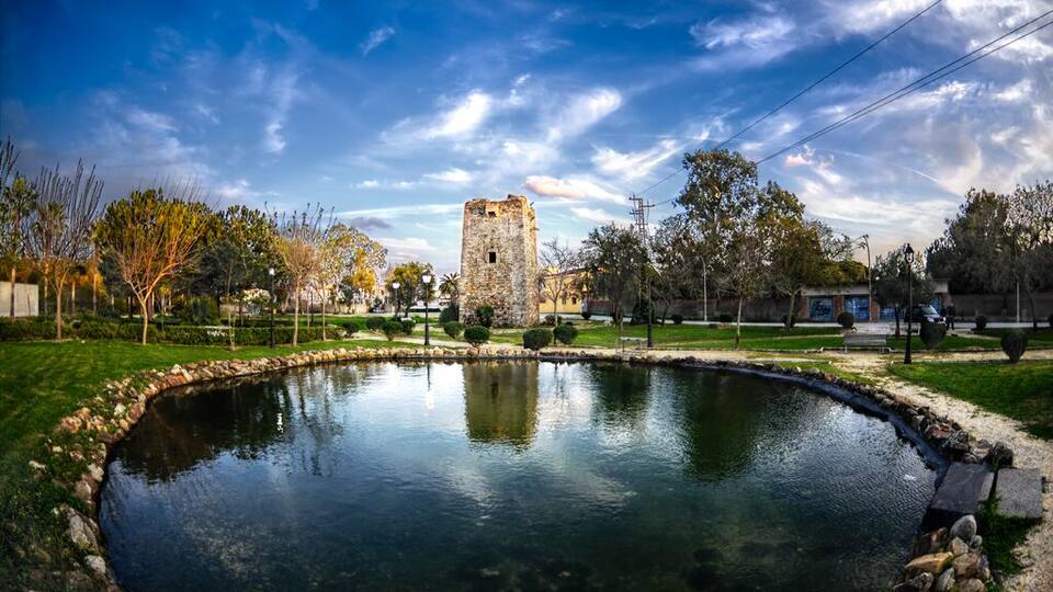 A pond with a stone tower in the background.