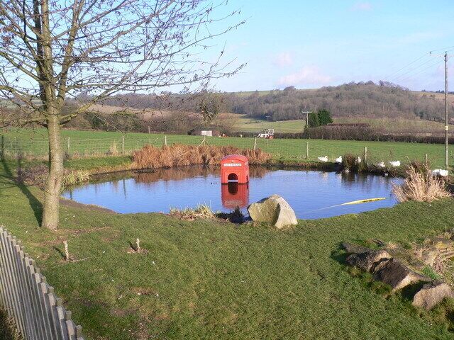 Phonebox in pub garden. Here's a shot of a rather interesting phone box in the heart of the Chilterns. The pond is in the back garden of the Three Horseshoes pub at Bennett End. At night the box is often lit (with its original internal lights). The surrounding countryside is very popular with Red Kite spotters.