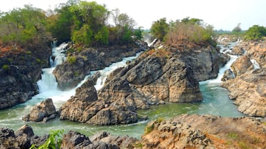 A multi-tiered waterfall surrounded by rocky terrain and dense greenery.
