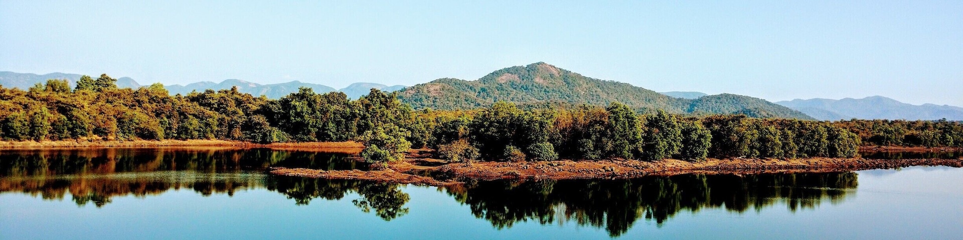 A calm lake reflecting trees and mountains.