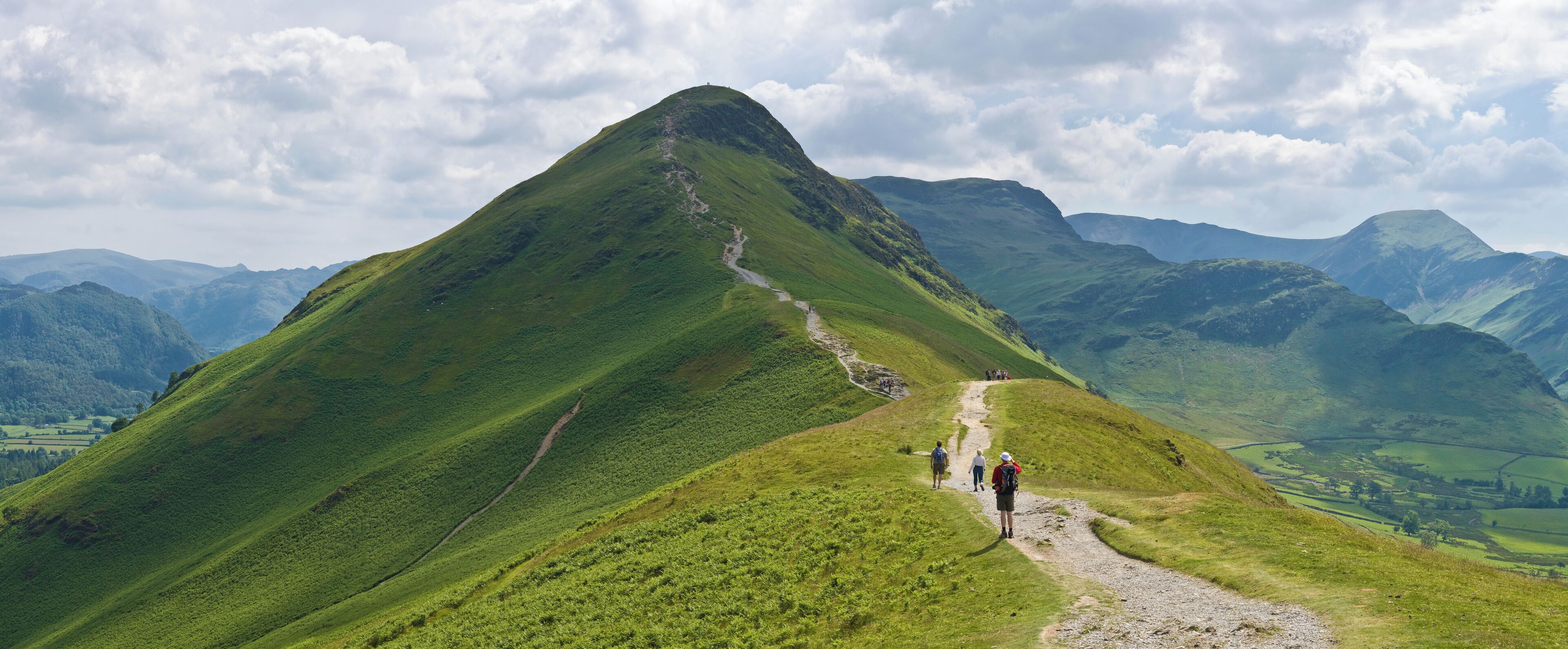 A mountain with a hiking trail and lush green valleys.