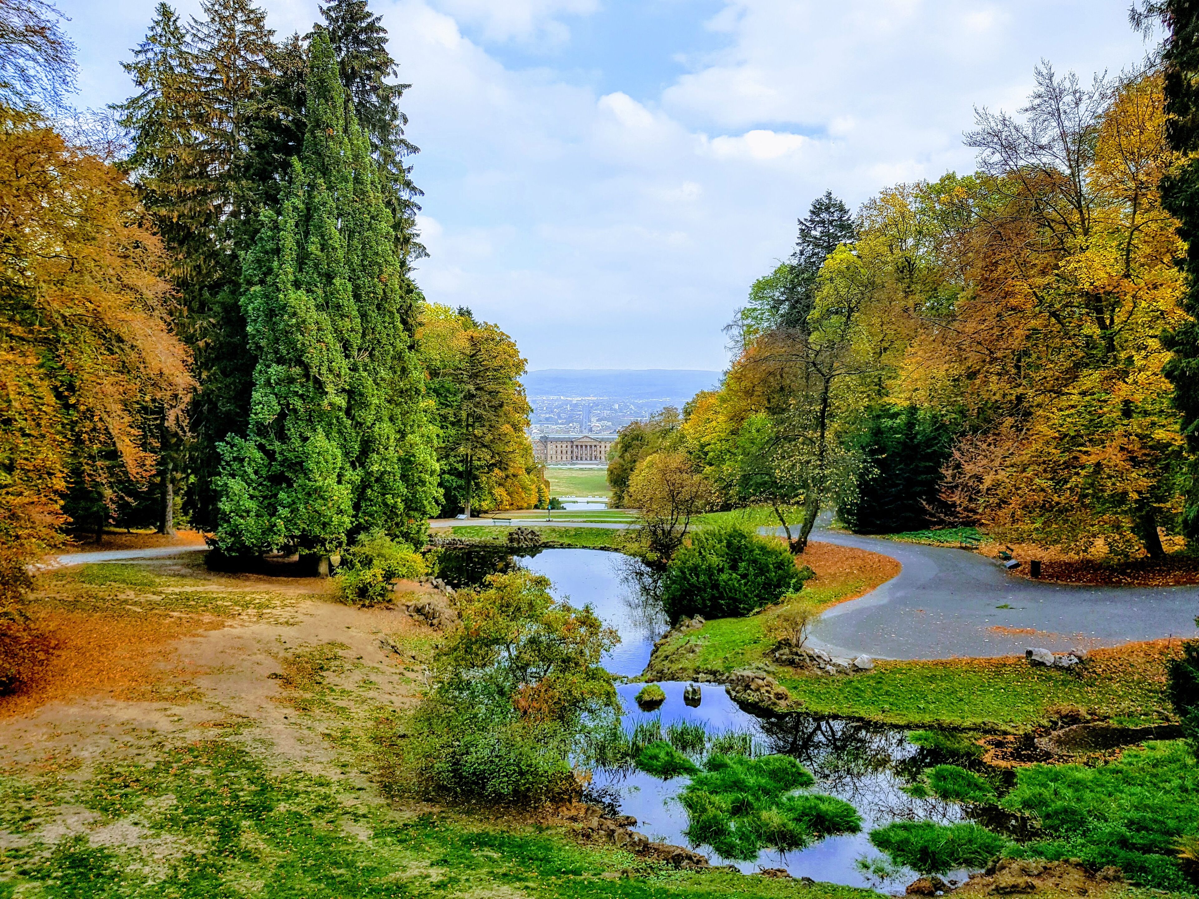 A serene landscape with a river, dense trees, and a distant view of a city.