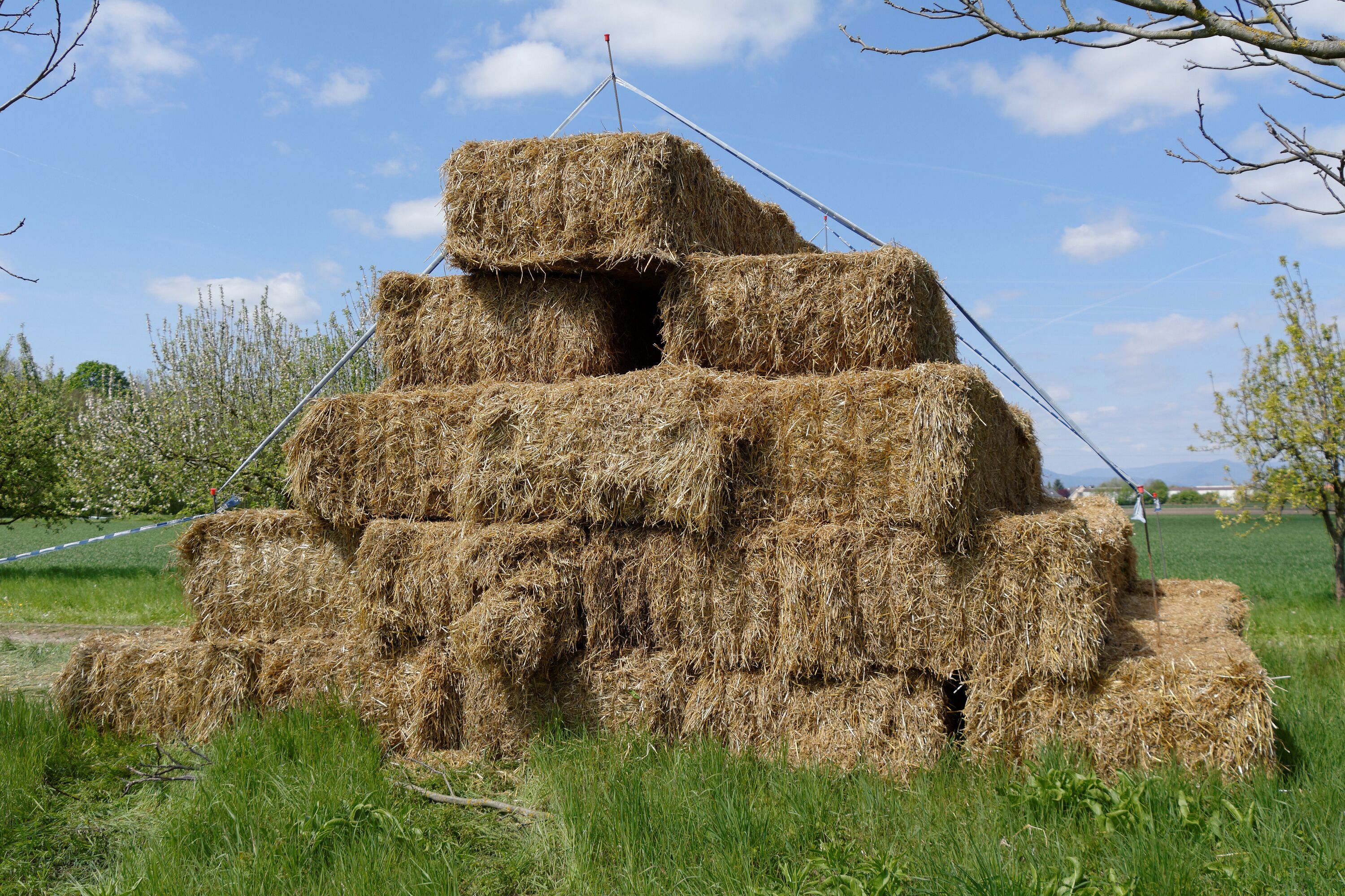 A stack of hay bales in a field with a clear sky.