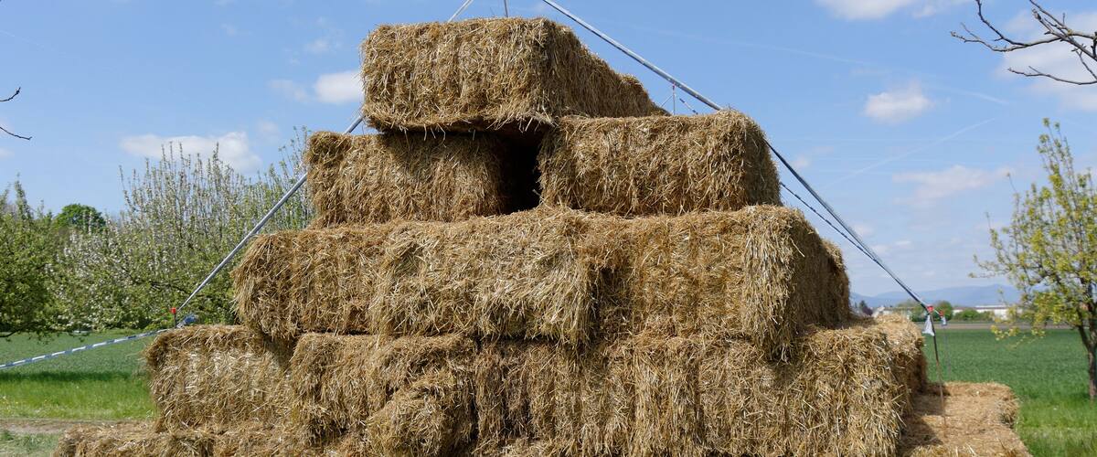 A stack of hay bales in a field with a clear sky.