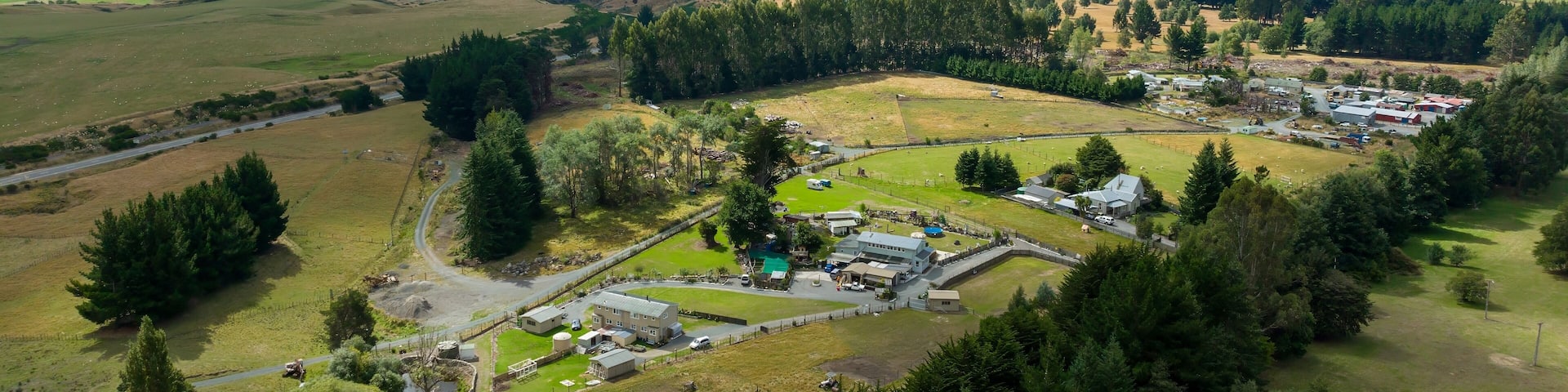 High-angle view of a rural farm, featuring buildings, pastures, and a mountain backdrop. Tranquil countryside scene. WAIOURU, MANAWATU-WANGANUI, NEW ZEALAND