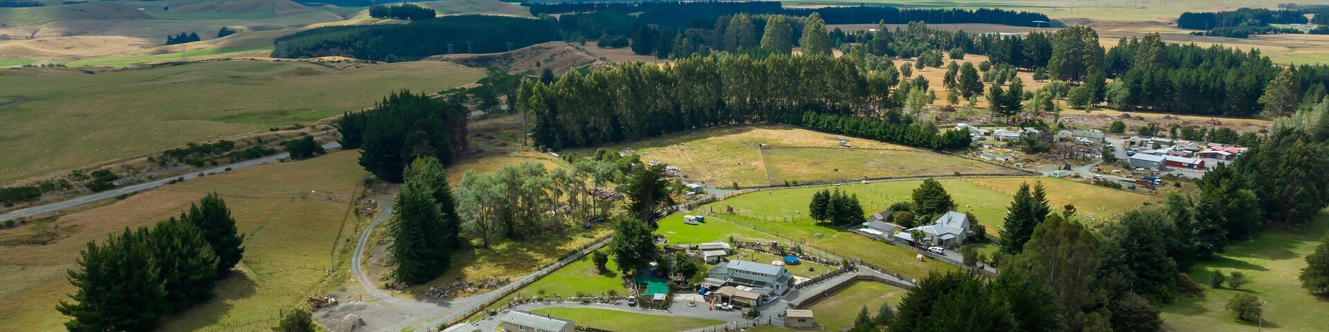An aerial view of a rural area with a small settlement, a river, and a mountain in the background.