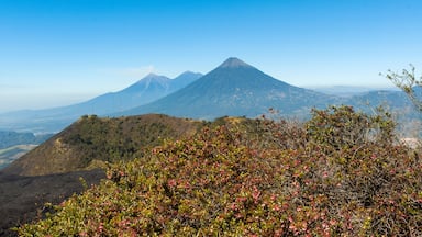 Paisagem montanhosa com um vulcão imponente e colinas ao redor.