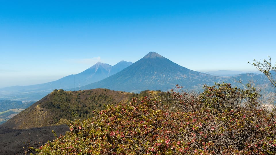 A mountain landscape with a prominent volcano and surrounding hills.
