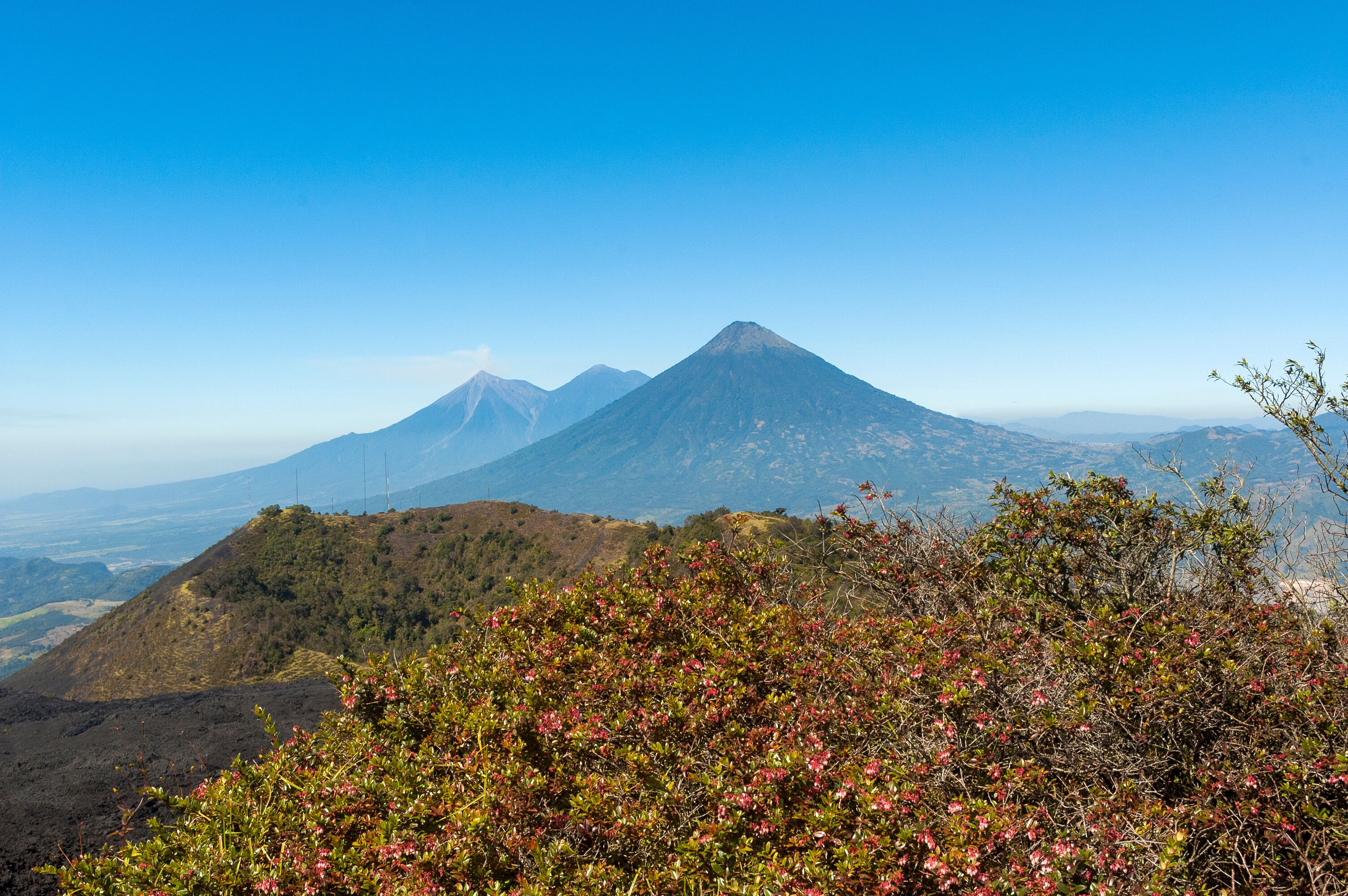 A mountain landscape with a prominent volcano and surrounding hills.