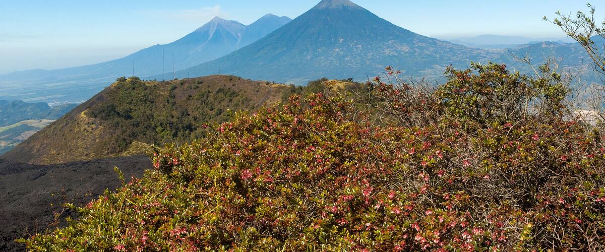A mountain landscape with a prominent volcano and surrounding hills.