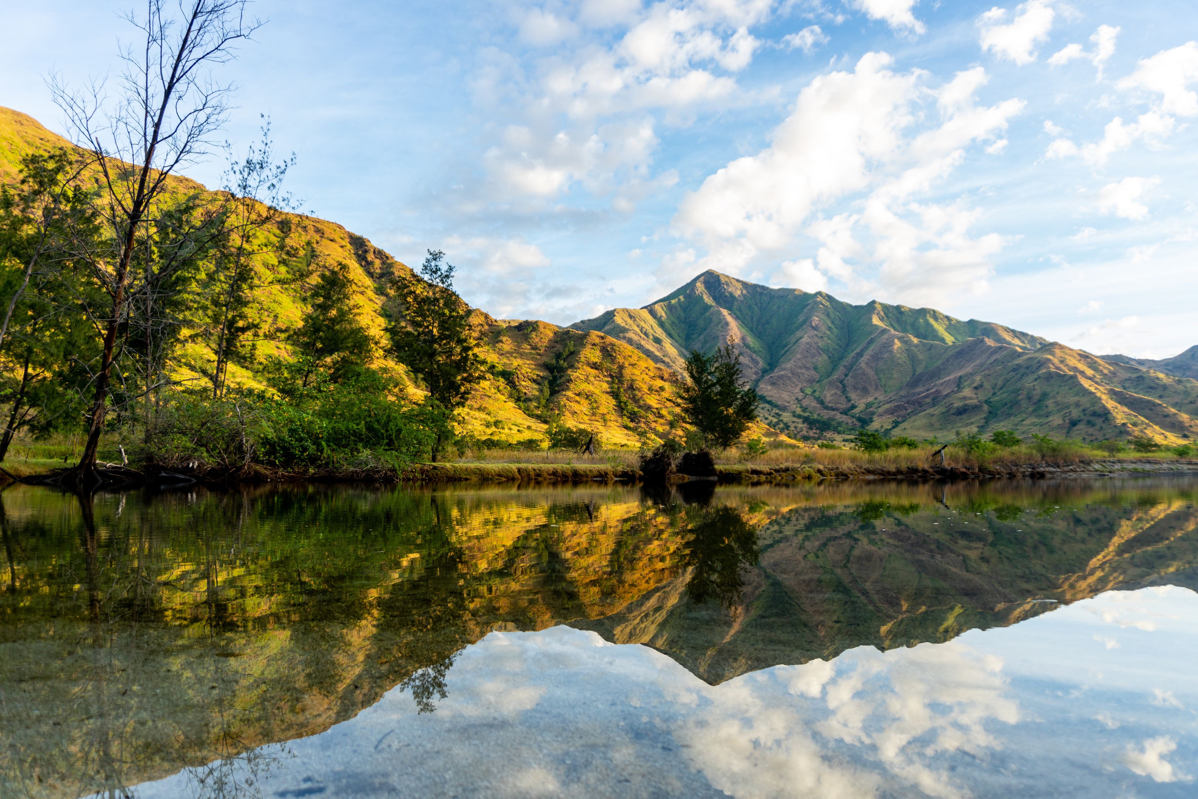A calm lake with clear reflections of the surrounding mountains and trees.