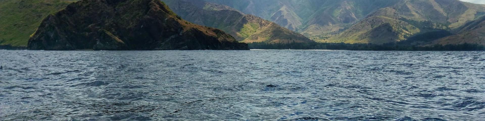 A mountainous landscape with a prominent rocky peak in the foreground and a body of water in the middle ground.