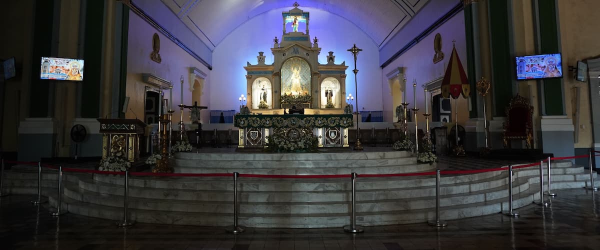 An ornate altar with religious statues and a large crucifix, surrounded by a red barrier.