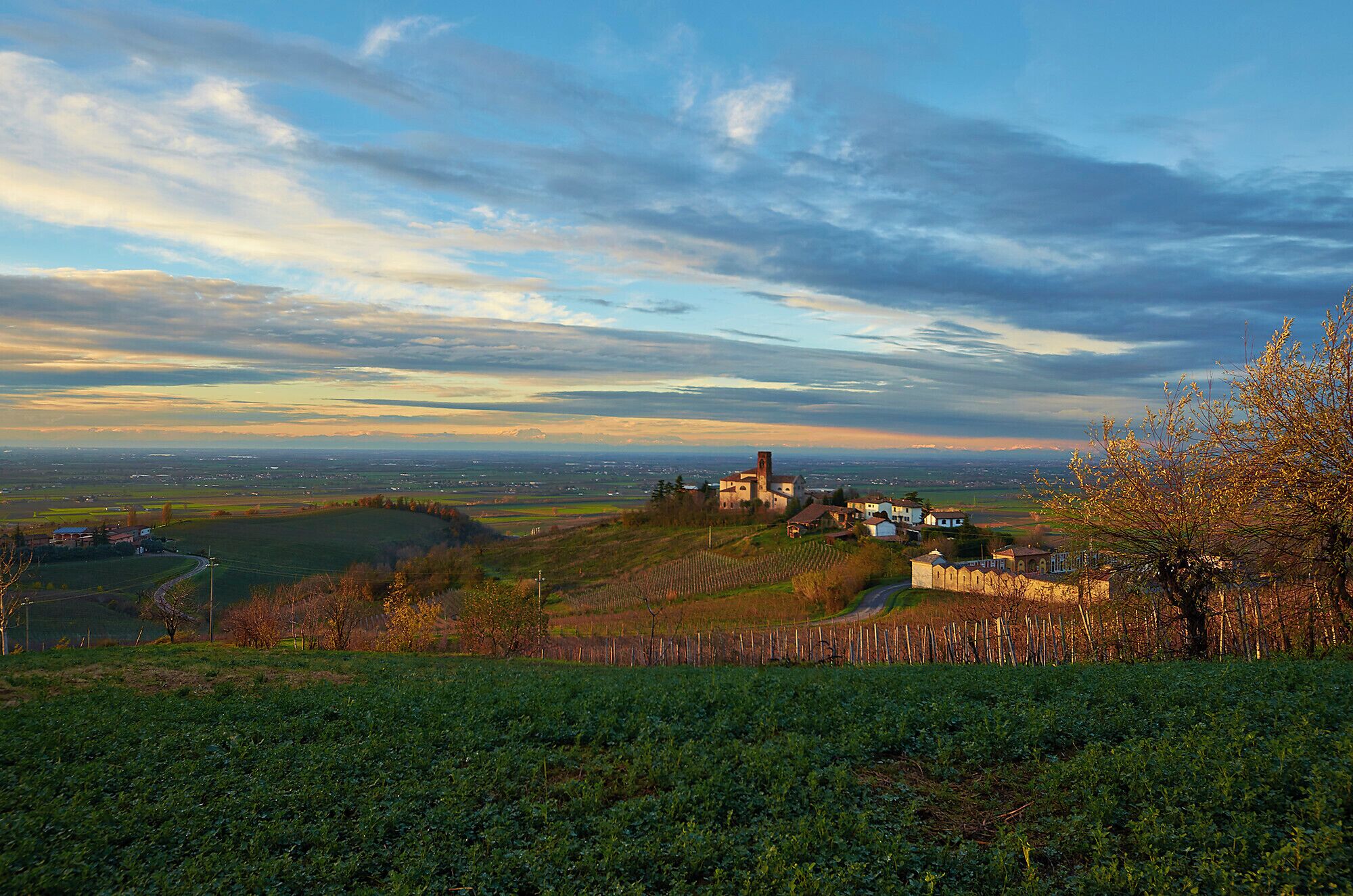 A rural landscape with a church on a hill, fields, and a distant view of a town.