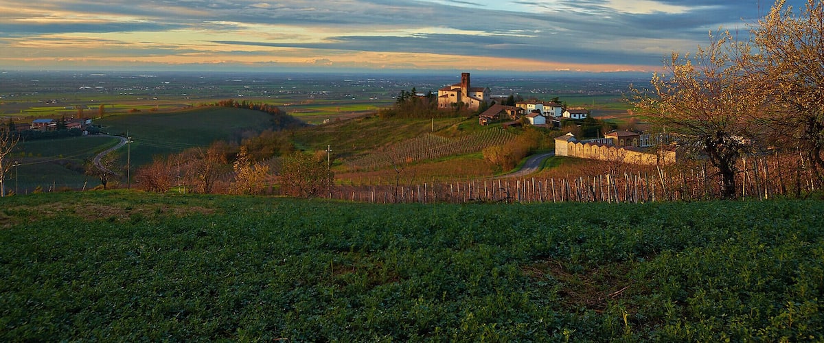 A rural landscape with a church on a hill, fields, and a distant view of a town.