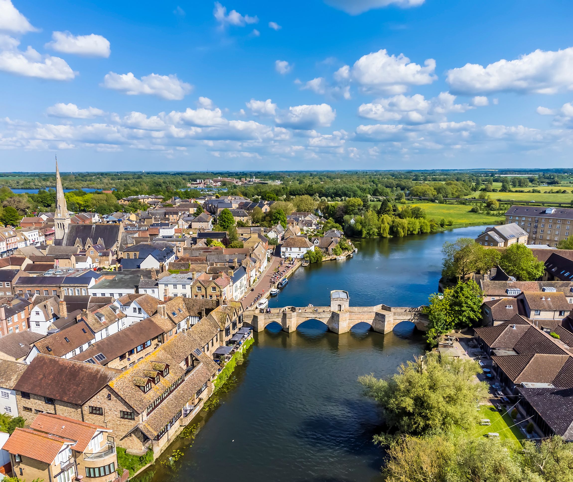 Ein Fluss fließt durch eine Stadt mit historischen Gebäuden und einer Brücke.