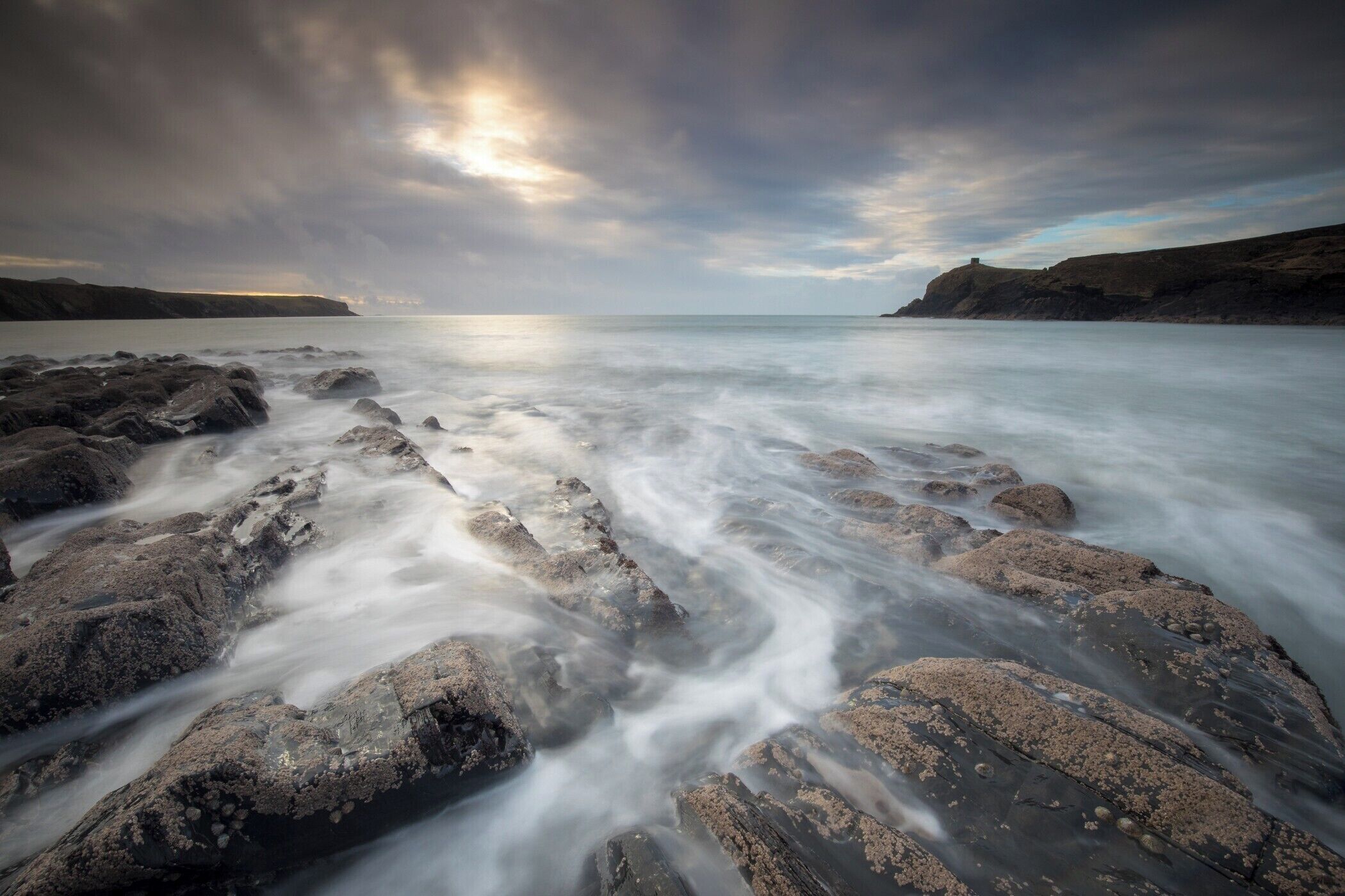 A rocky shoreline with a long exposure capturing the movement of water.