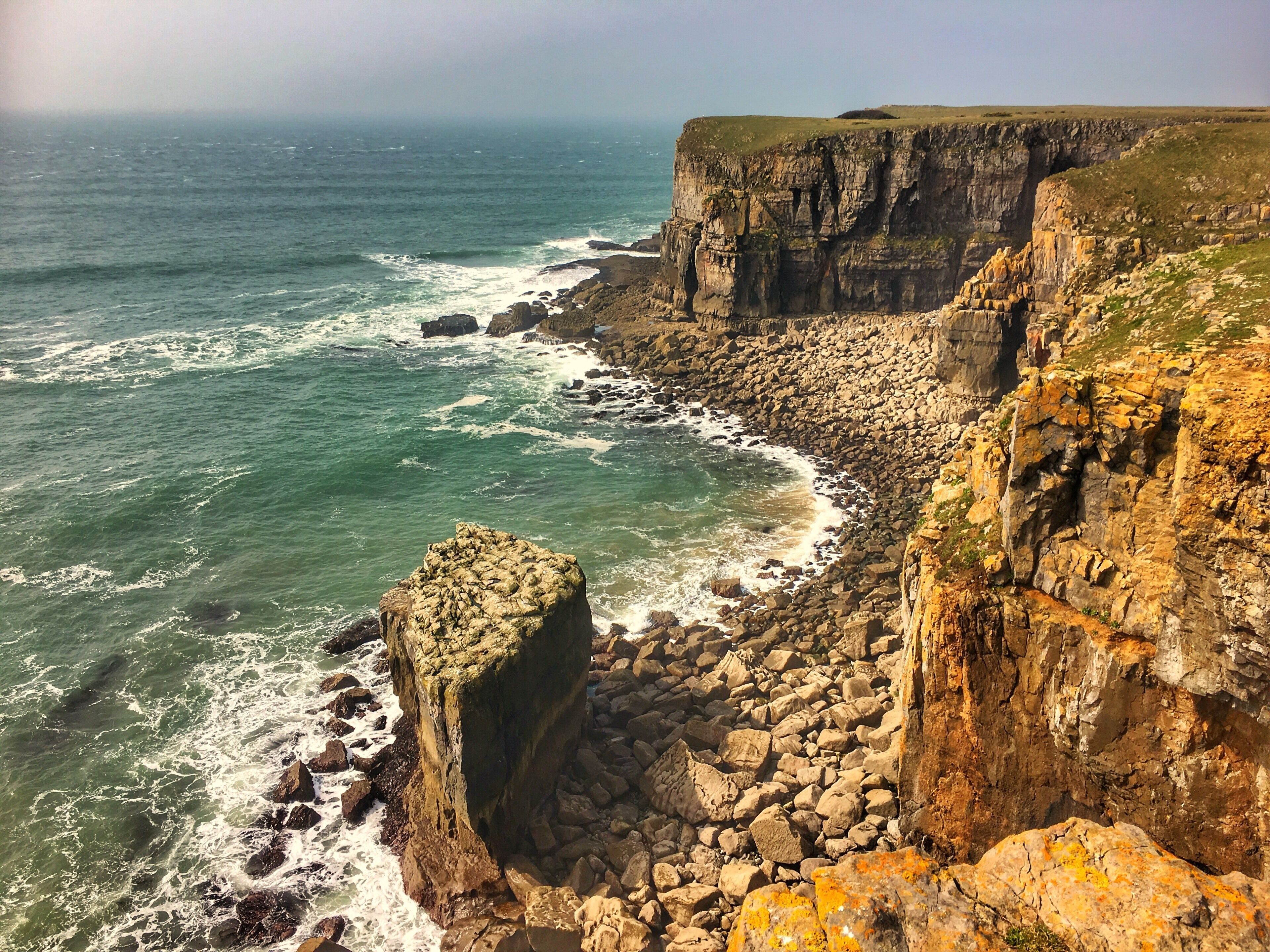 A coastal cliff with waves crashing against it.