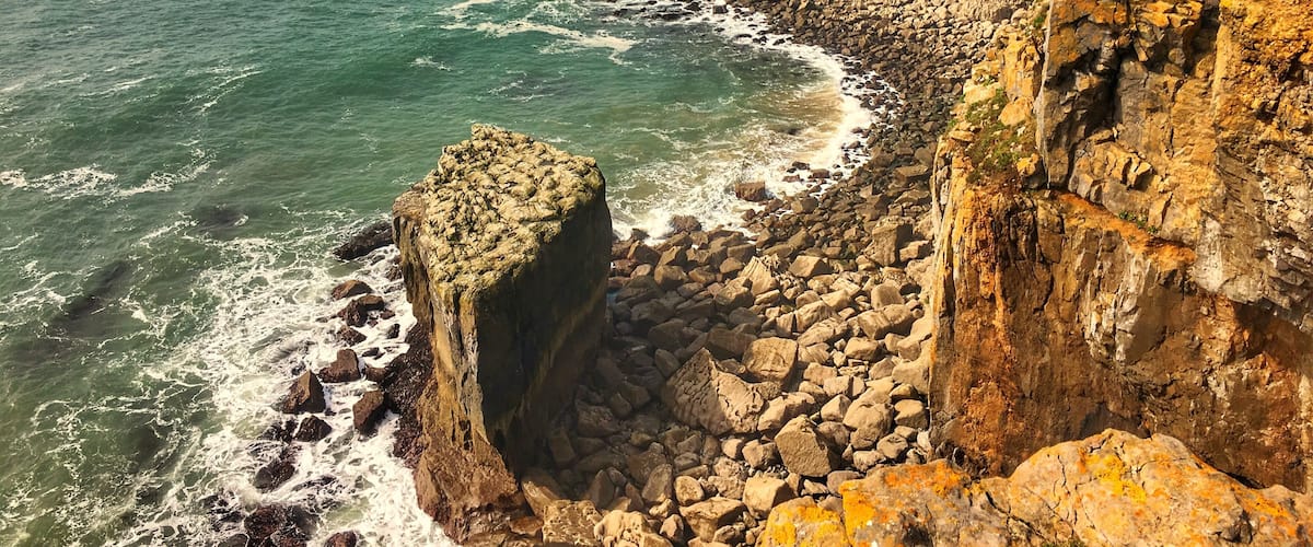 A coastal cliff with waves crashing against it.